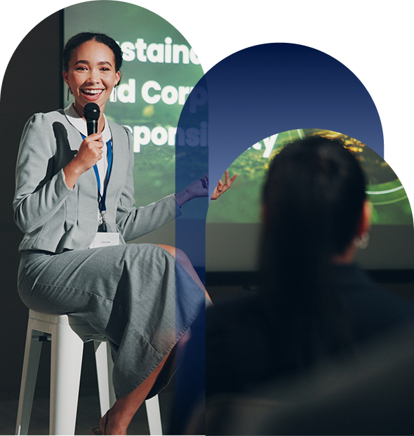 A woman sitting on a chair giving a lecture in front of a crowd